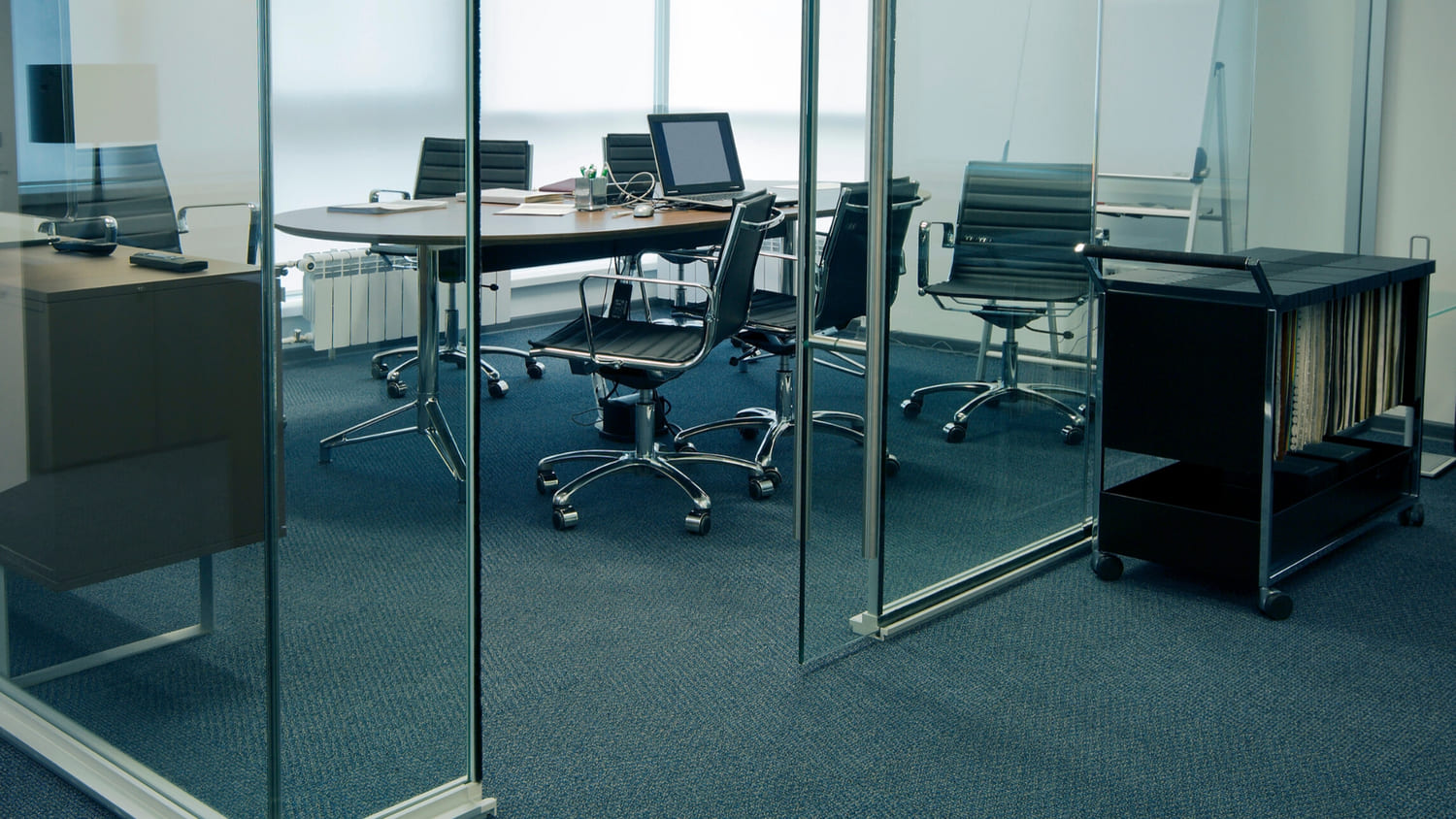 An office space and conference area with dark commercial carpet